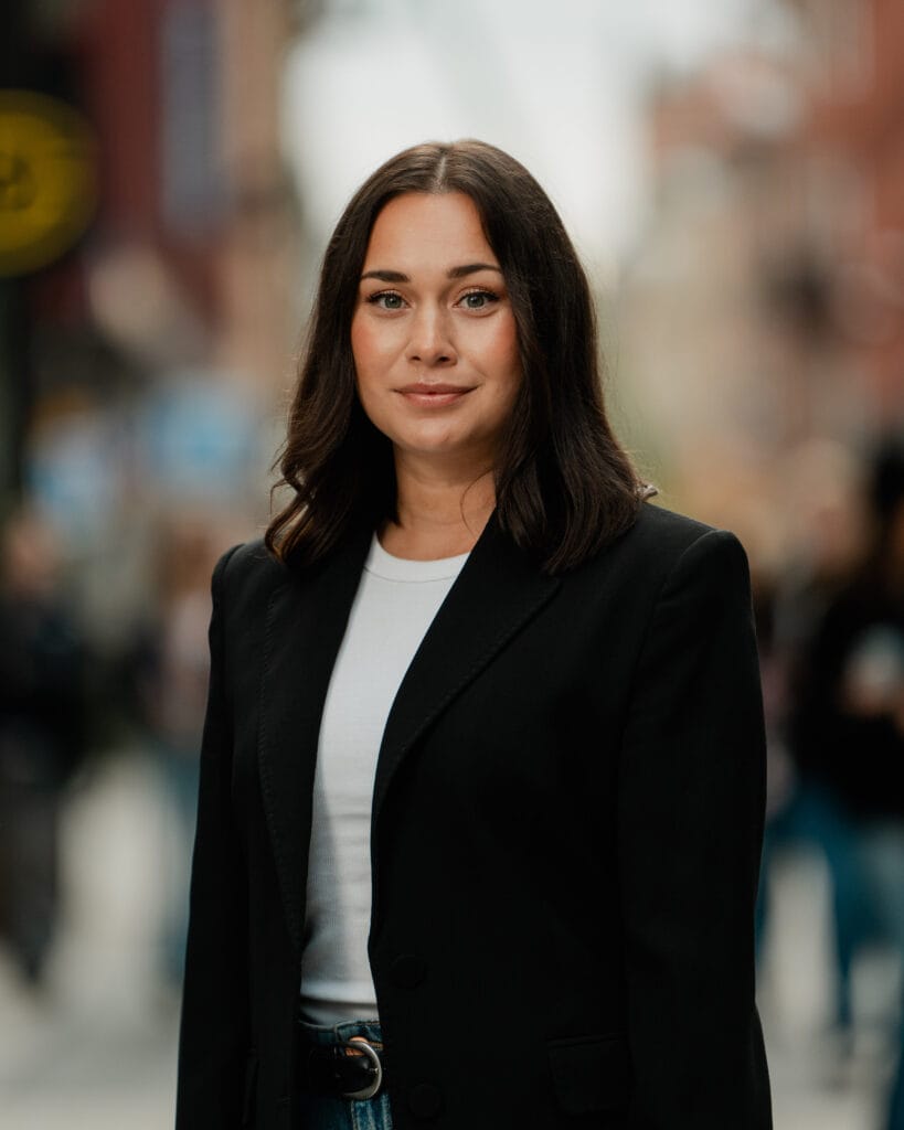 Kvinna i affärskläder står på stadsgata, representerar professionell konsultverksamhet inom stadsutveckling