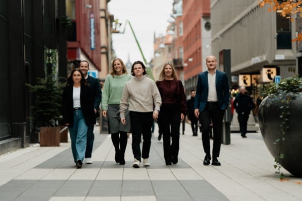 Vanliga frågor och svar - Grupp om sex personer går tillsammans på en urban gågata med butiker och restauranger